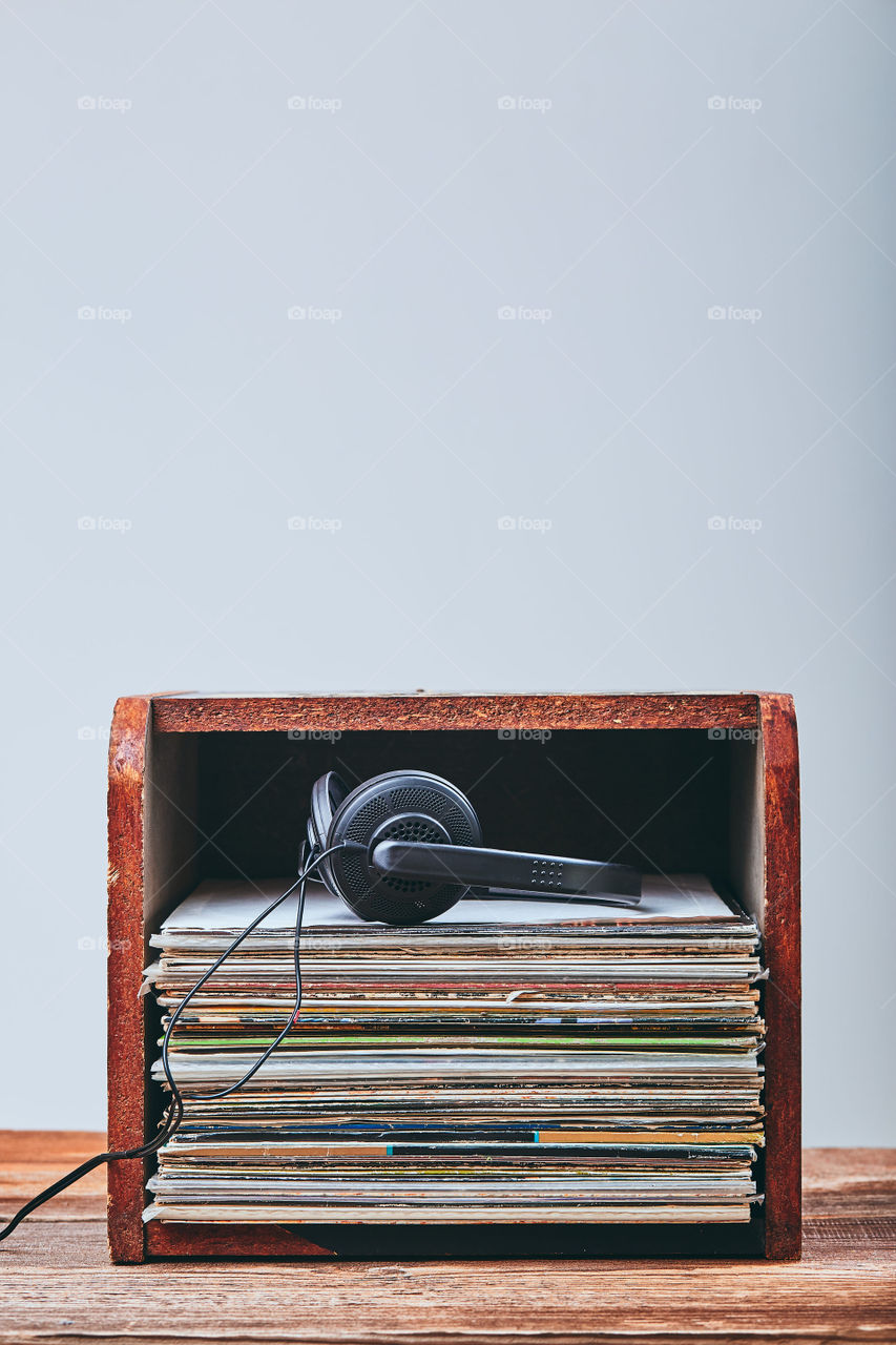 Stack of many black vinyl records and headphones put on the top of stack. Candid people, real moments, authentic situations