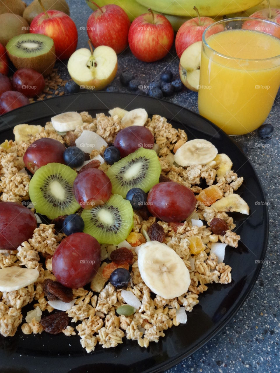 Healthy breakfast of crunchy flakes kiwi, banana, grapes, berries, raisins and fresh orange juicy drink