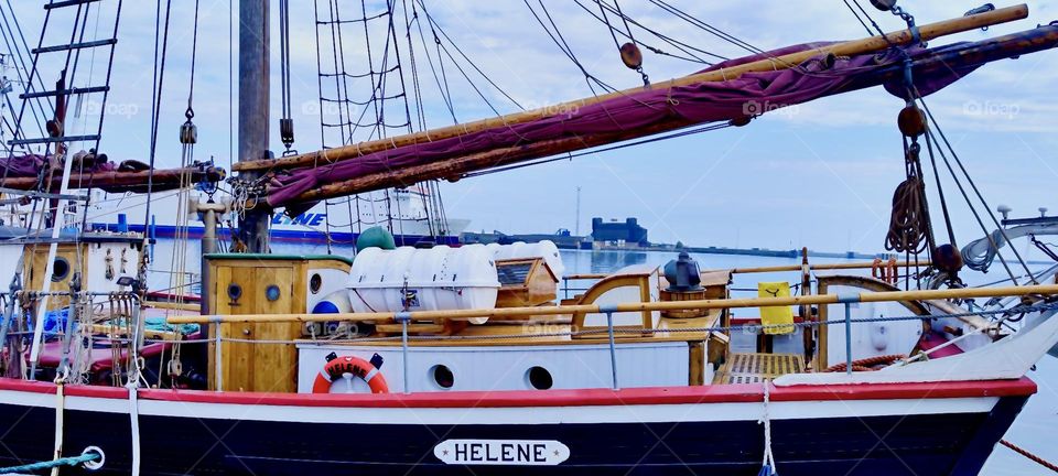 This antique sailboat called “Helene” is lying at the shore of “Ystad” in “Sweden” by the “Baltic Sea”. The main sail is currently rolled up for more seafaring adventures in the future. 2023. Hypnotic Productions