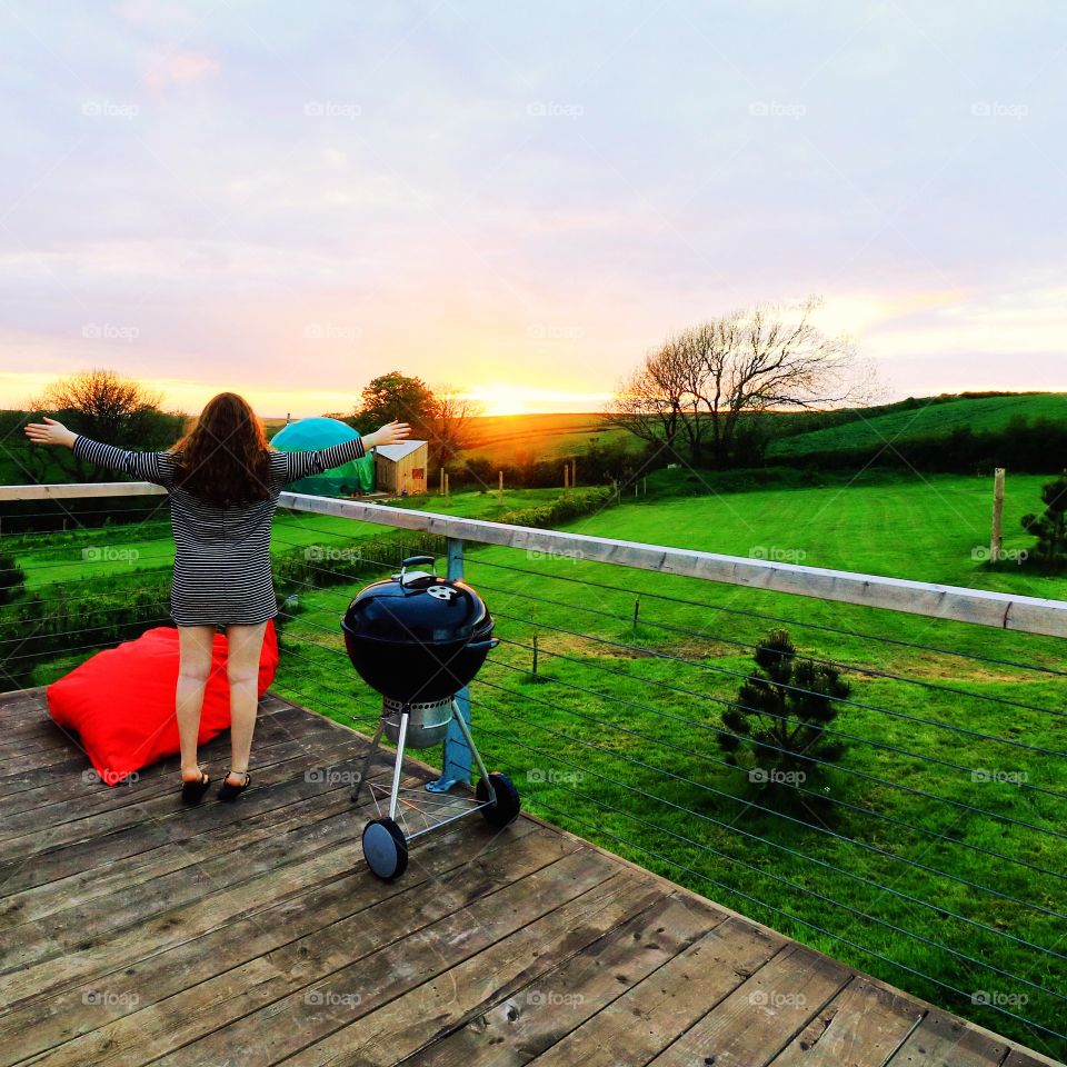 Woman outstretching arms in front of grassy landscape