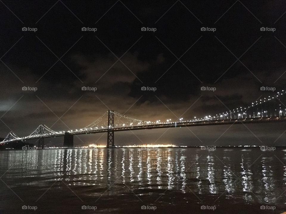 White lights on San Francisco Bay Bridge reflecting on the water of the bay at night