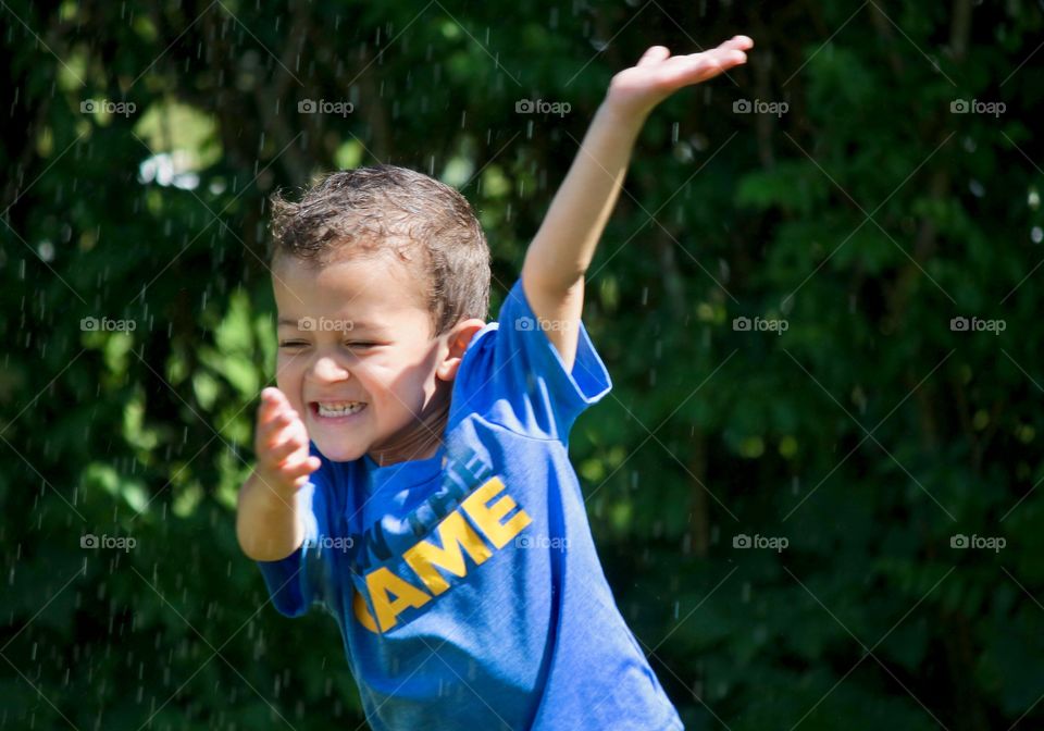 Boy running through the sprinkler 