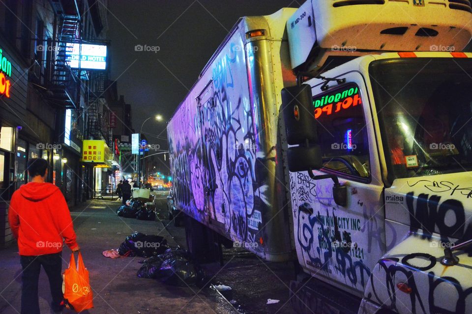 Night time NYC Chinatown street, truck with graffiti, garbage bags, unrecognizable man walking