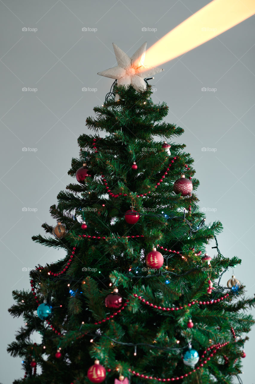 Christmas tree with star on the top and illuminating blurred light