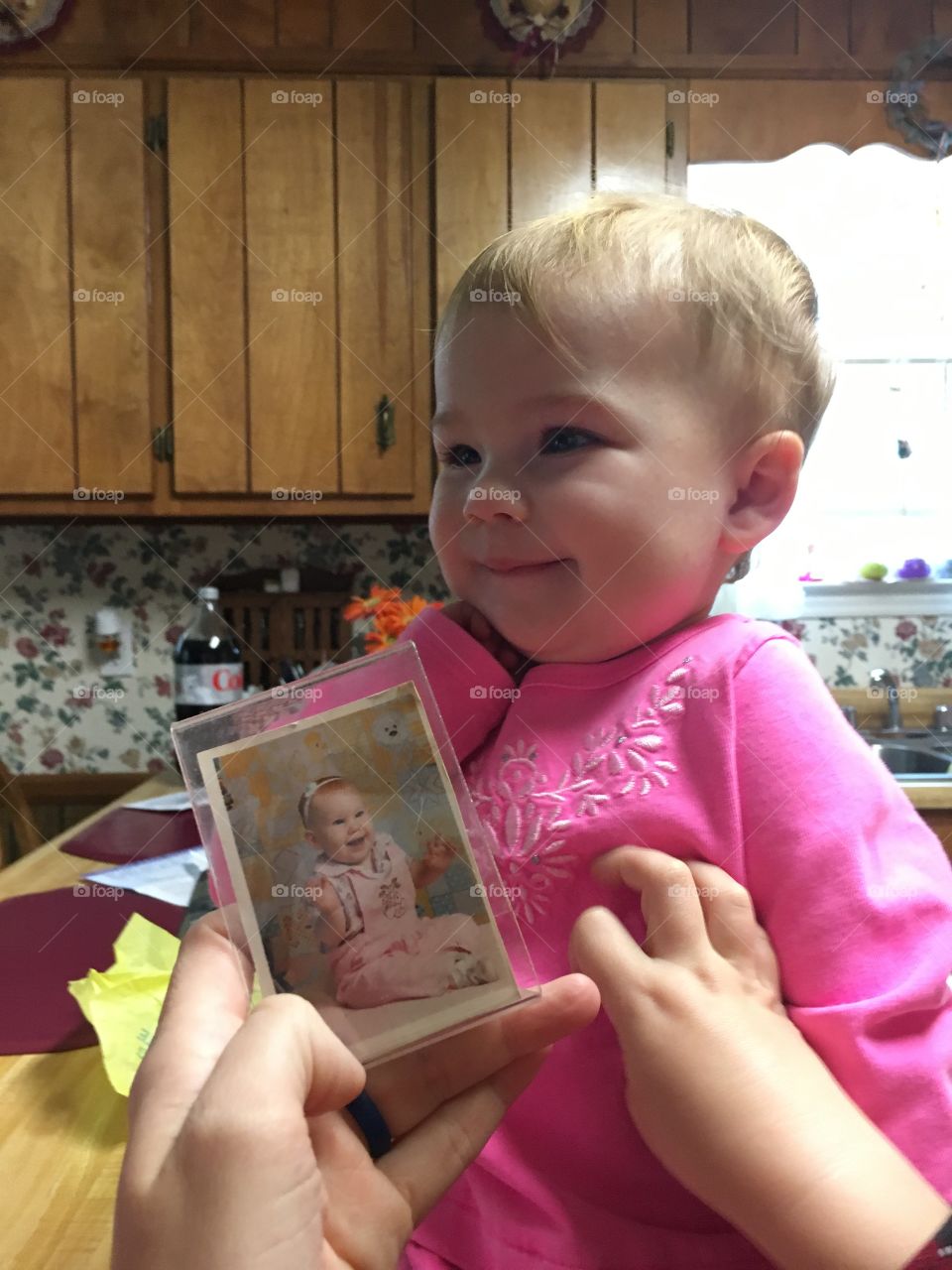 Human hand holding photo frame in front of cute baby