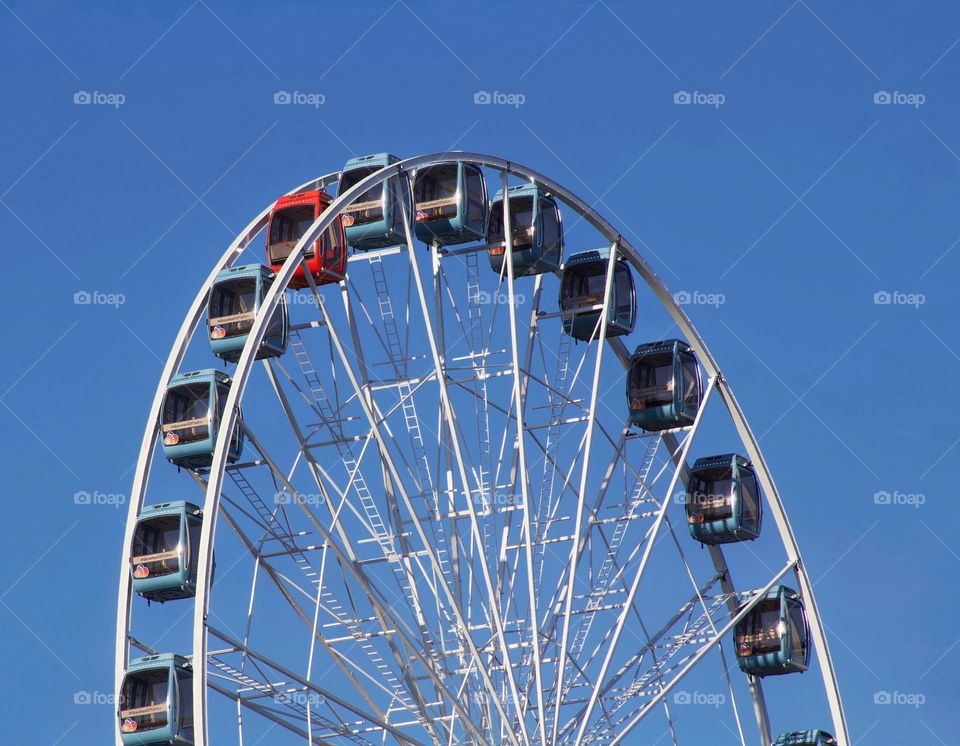 Ferris wheel with a red cabin amongst the blue cabins in Tallinn, Estonia.