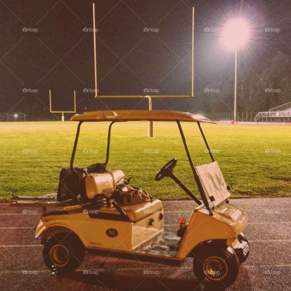 A golf cart parked by a football field.