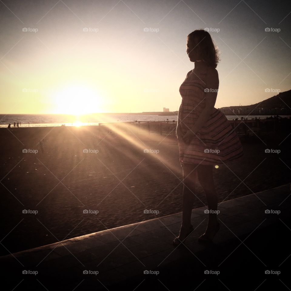 Under sunset. A young woman walking on the beach in the sunset time