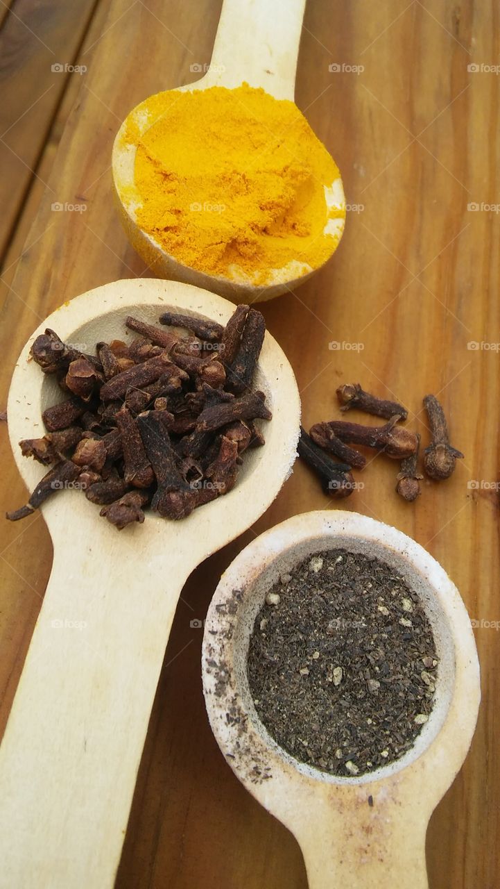 turmeric pepper cloves spices wooden spoons wood cooking color health