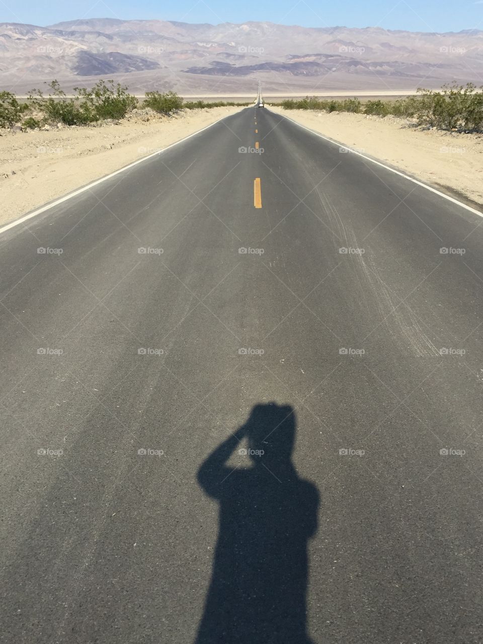 Man's shadow on the road takes a photo