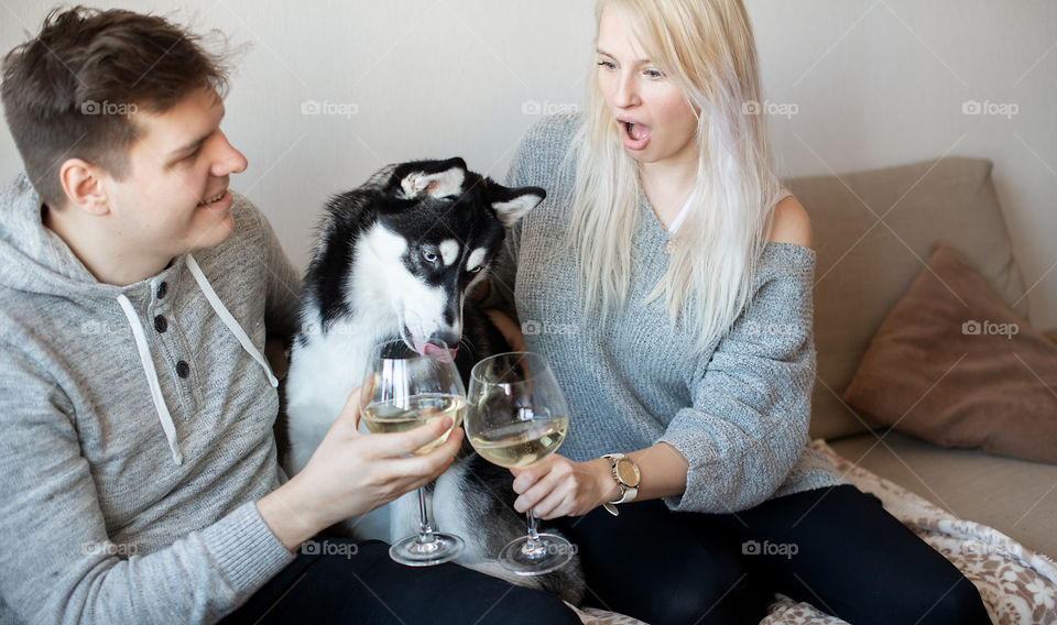 Cute couple and dog drinking white wine from big glasses