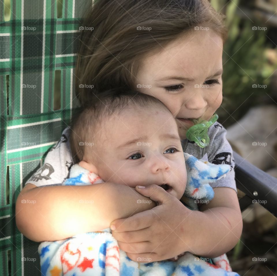 Close-up of a cute brother and sister with pacifier in mouth