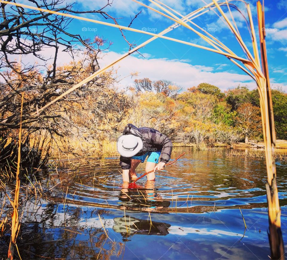 Catching tadpoles in the shallow pond with a red net