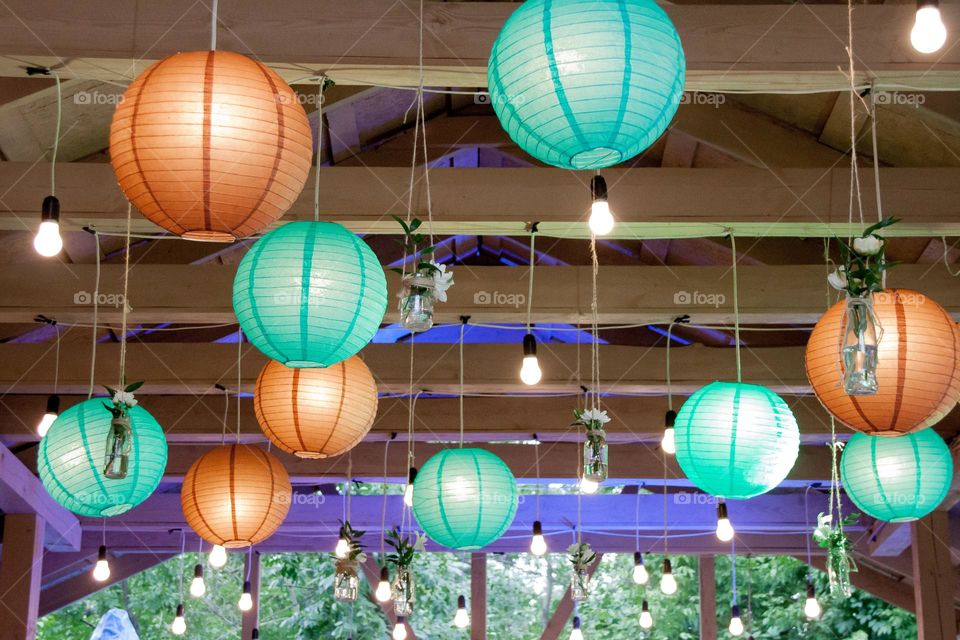 Paper lanterns hung from the ceiling art a wedding reception indoors