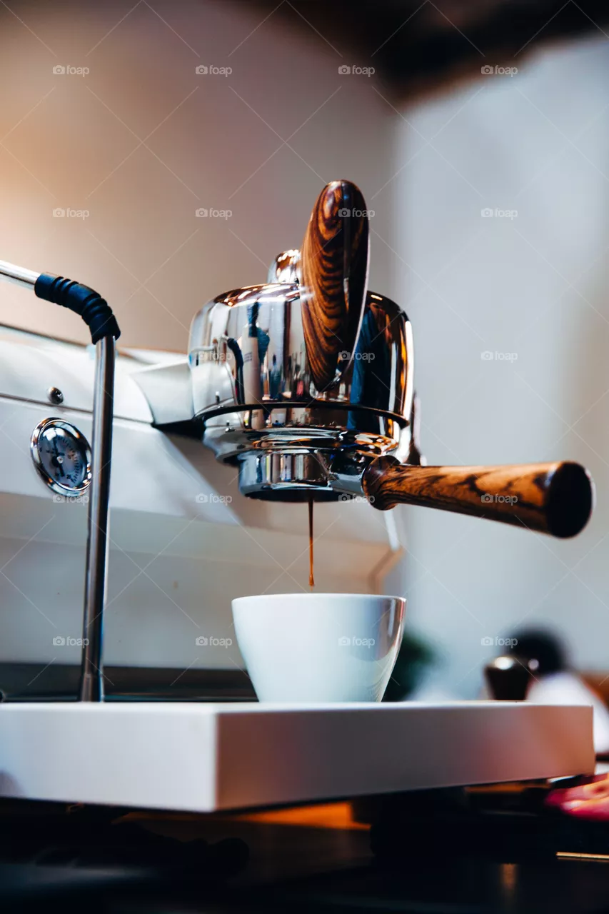 An coffee machine with polished wood handles making a fresh espresso.