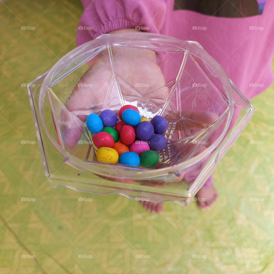 Colorful candies in plastic bowl on palm