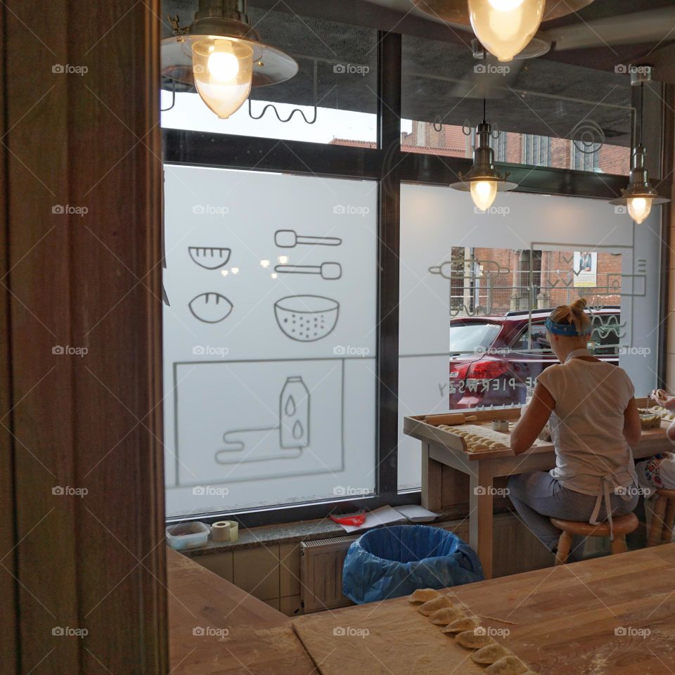 Lady sat working inside a restaurant in full view of customers and passers bye the window 