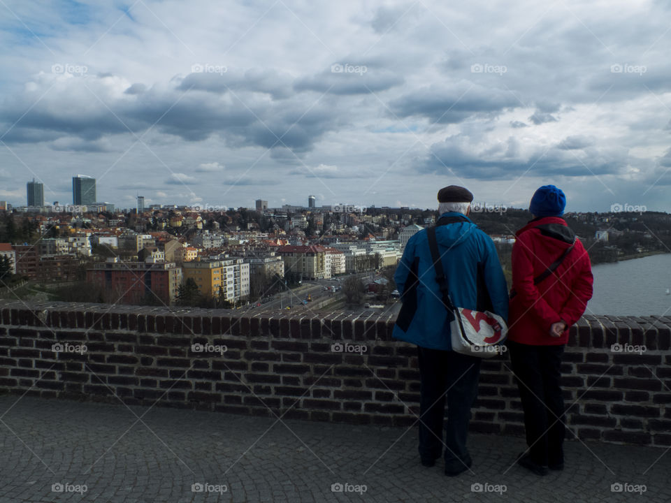 An elderly couple is watchong the view of Prague, Czech Republic.