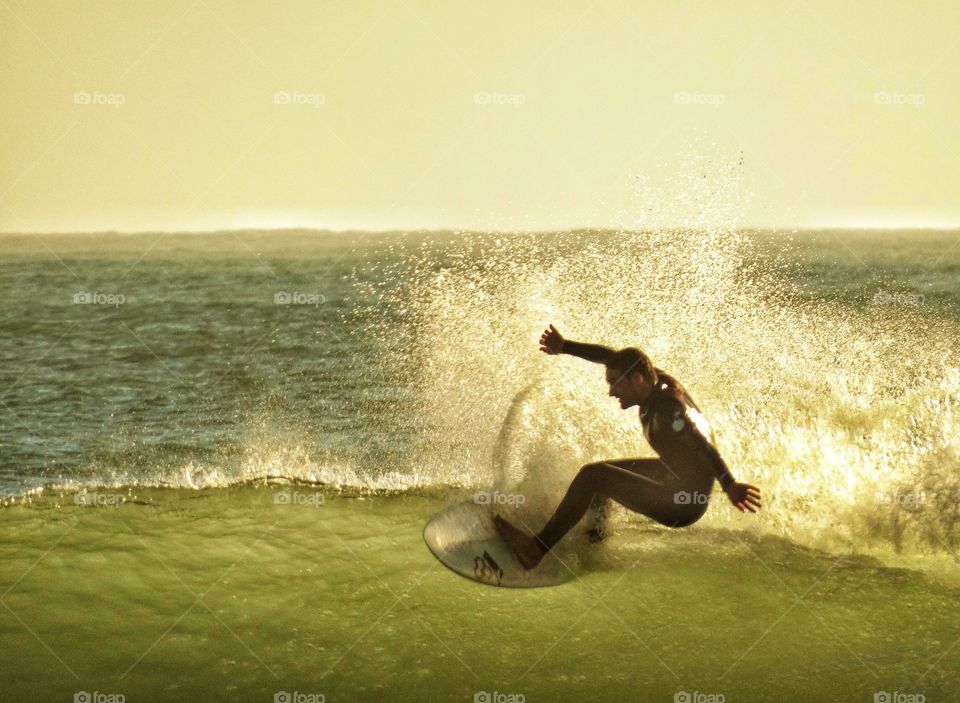 Surfing During The Golden Hour. Epic Surfer Before Sundown
