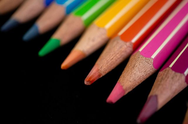 Colored pencils in a row with a black background