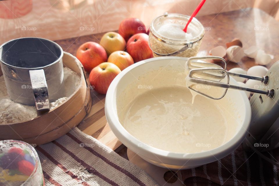 Making an apple pie dough using eggs, flour, sugar and apples.