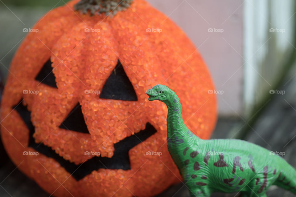 A dinosaur with a pumpkin.