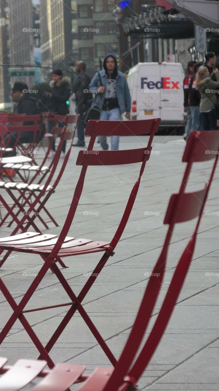 Red Chairs in a Line in the City with People in the Background