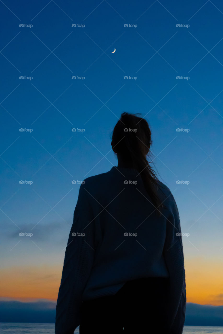 Girl watching the beautiful sunset and leaving all troubles behind her back.