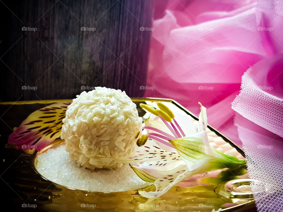 white chocolate on a sugar covered golden plate decorated with a flower, covered with coconut pieces sweeeeeeet