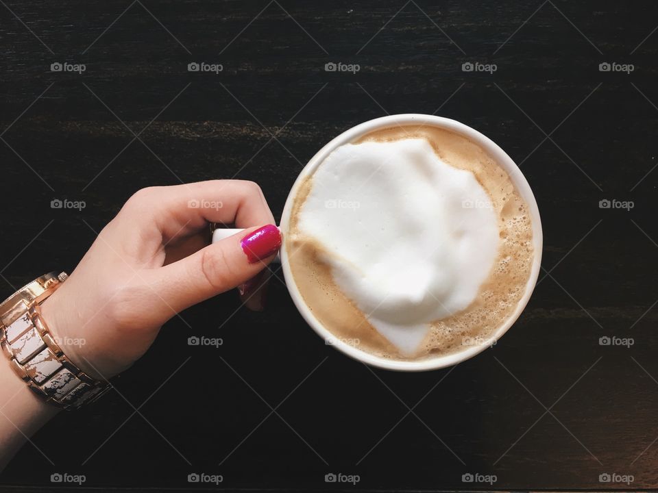 Women's hand holding coffee cup