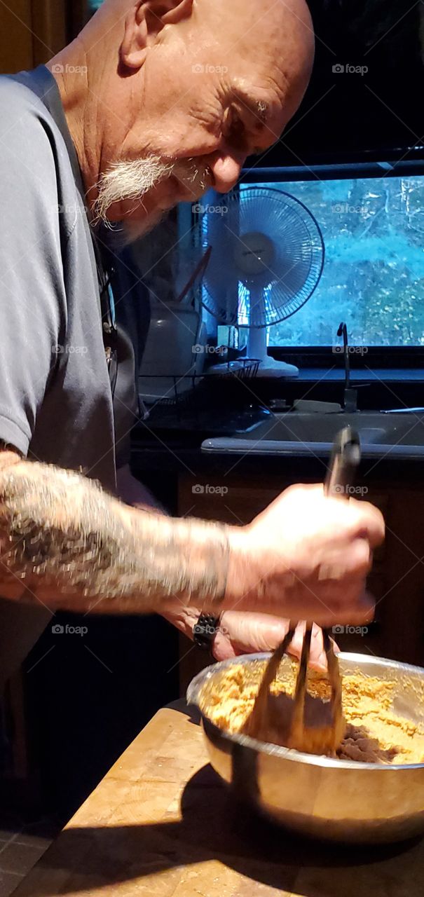 Man wisking bowl of muffin mix, readying to pour into muffin tins.