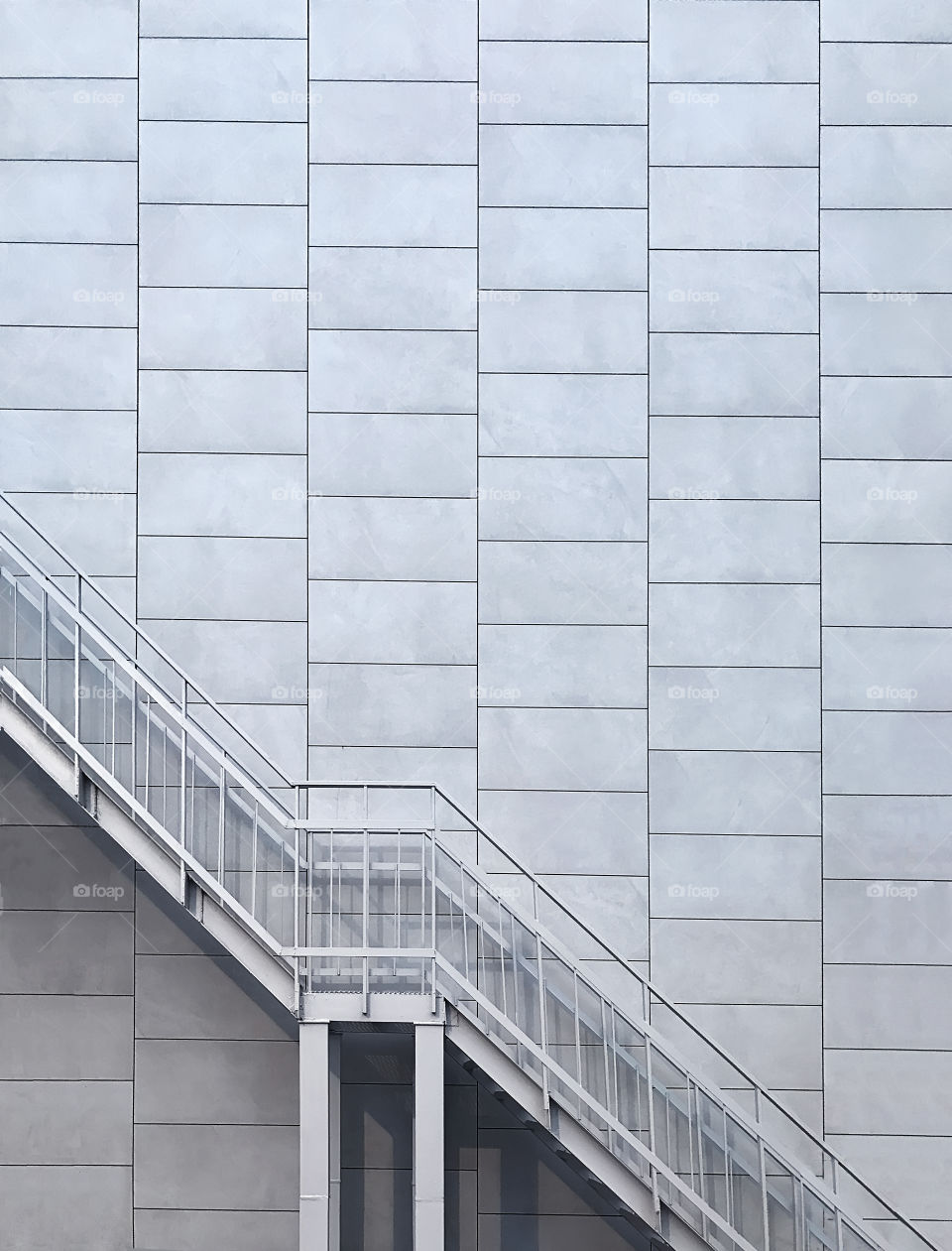 Metal staircase on grey geometric wall background 