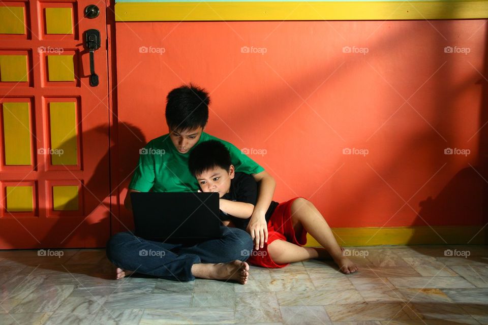 young asian children with a laptop computer in a living room and happy