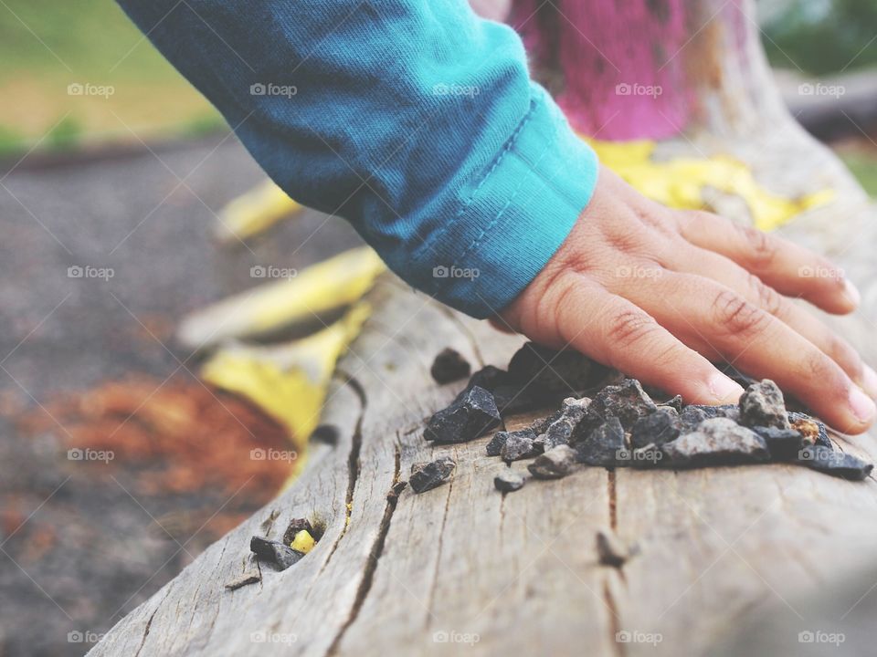 hand of Child playing with stones painted trunk