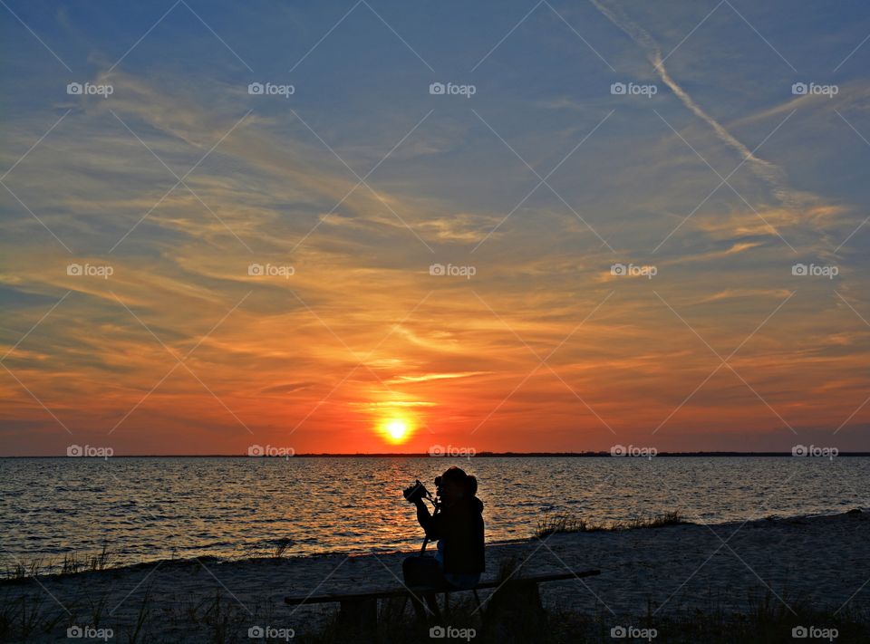 A photographer searches for the best position to set her tripod and camera up to capture the spectacular sunset