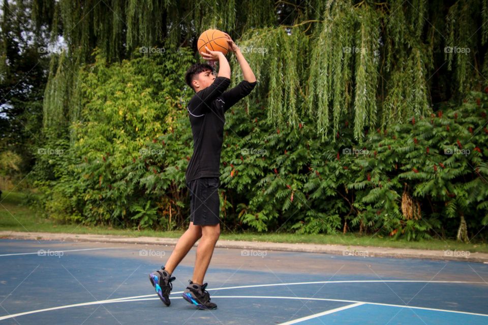 Young man is throwing a ball into the basket