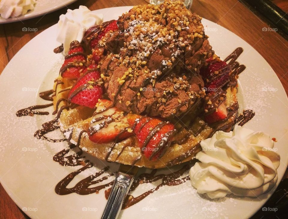 Waffles with strawberries and chocolate Roche ice cream, Nutella drizzle and whip cream. 