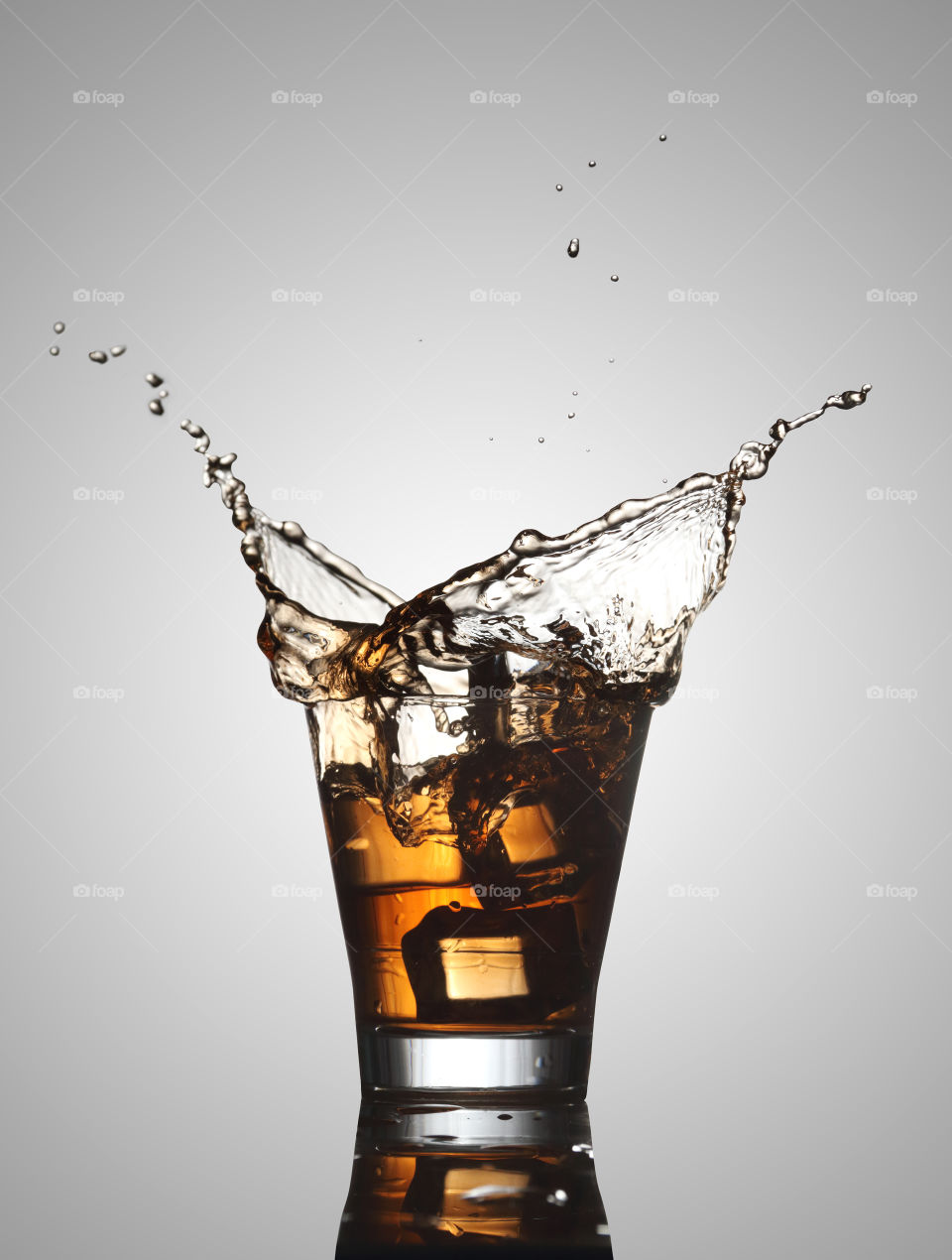 Ice cube splash into a whiskey, rum glass