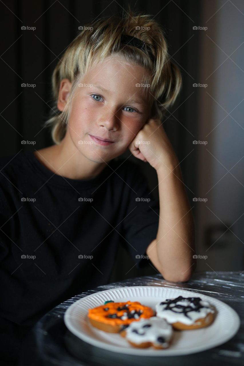 A seven year old child makes handmade cookies for Halloween.