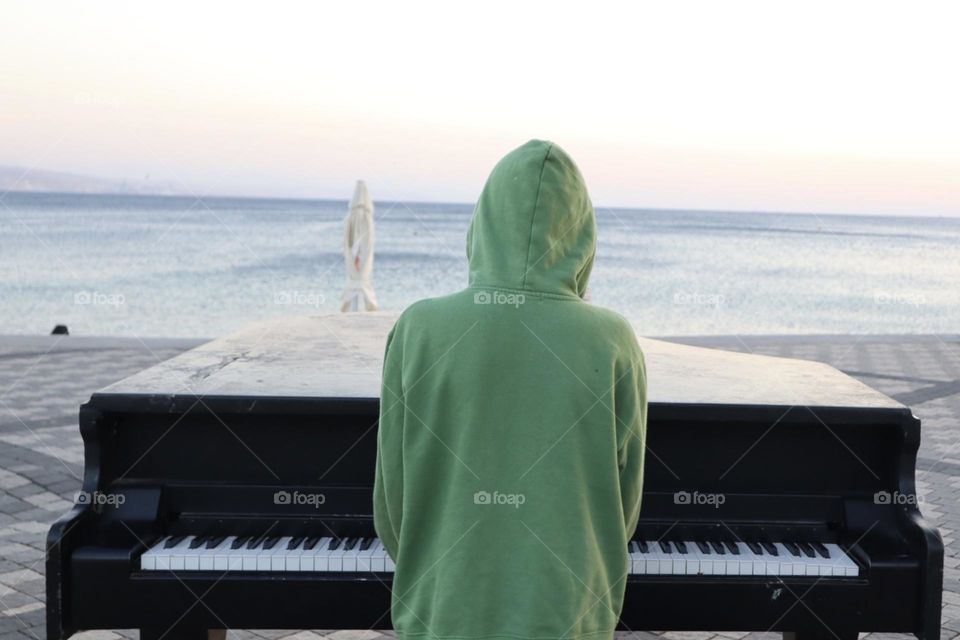 Boy with green shirt playing piano on the beach
