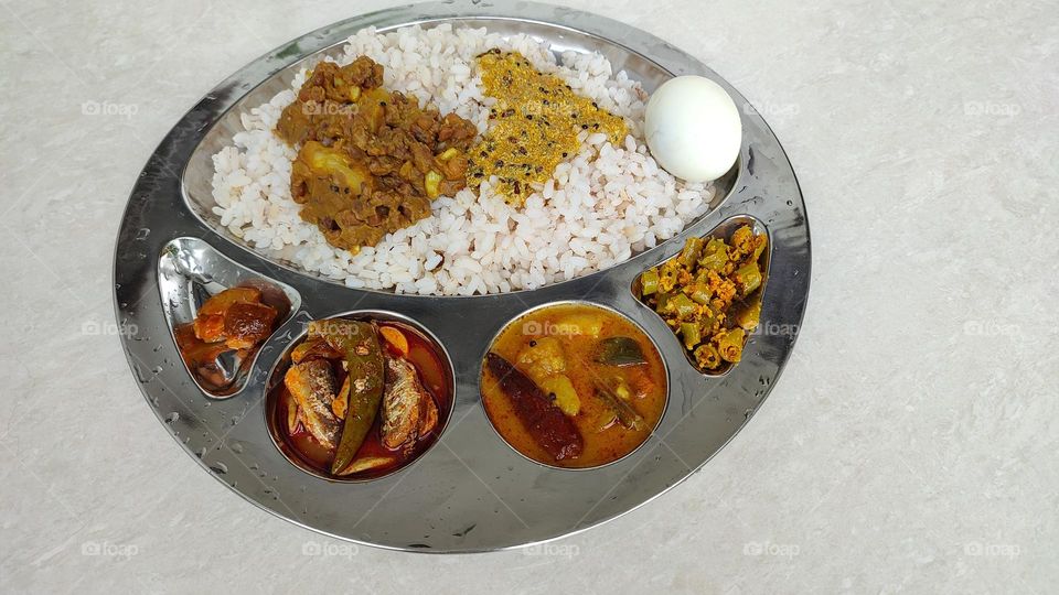 Indian Meal, Indian food, rice thali contains pickle, fish curry, sambar (vegetable curry), thoran, boiled egg, curd curry, cowpeas and yam dish finally Rice, bon appetite