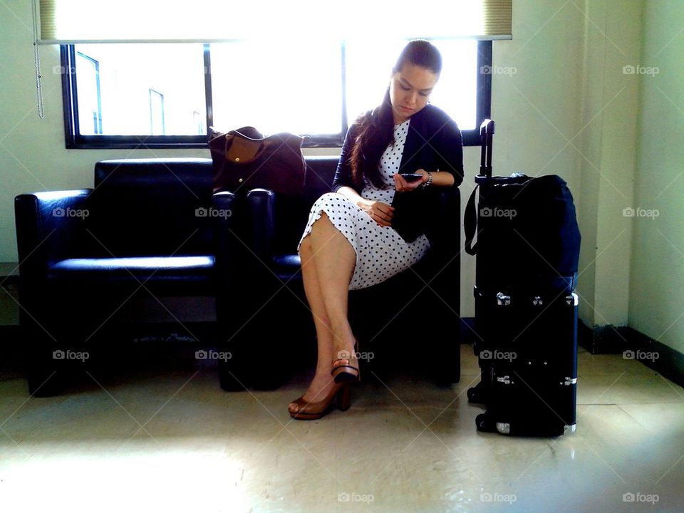 lady on a couch with a cellphone and luggages