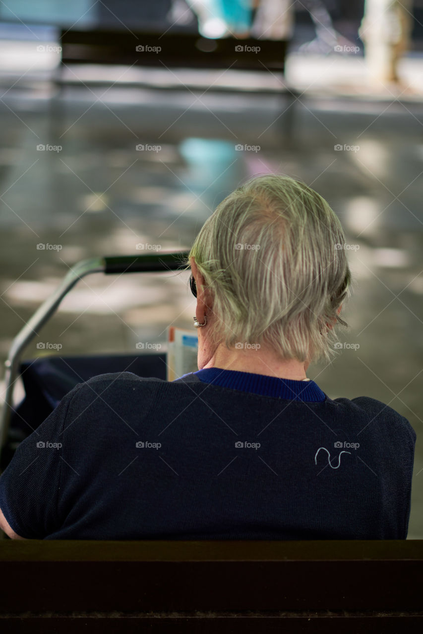 Elderly woman sitting in a street bench