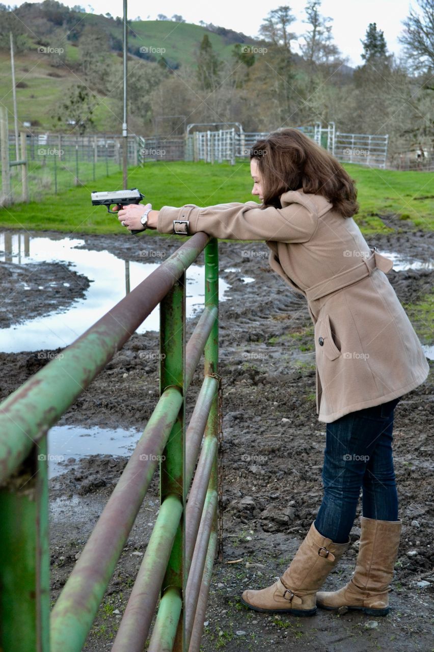 Girl shooting a gun on a gate