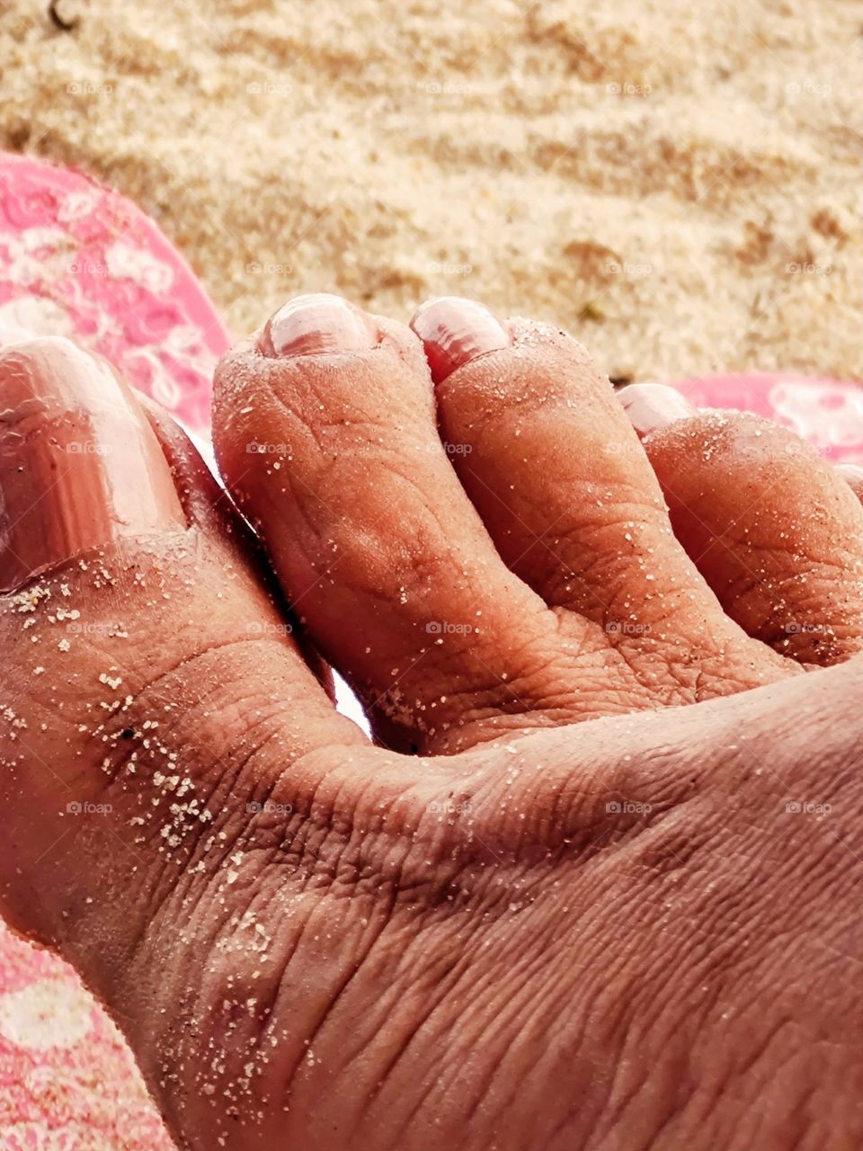 On a beach vacation with bare feet in the sand.