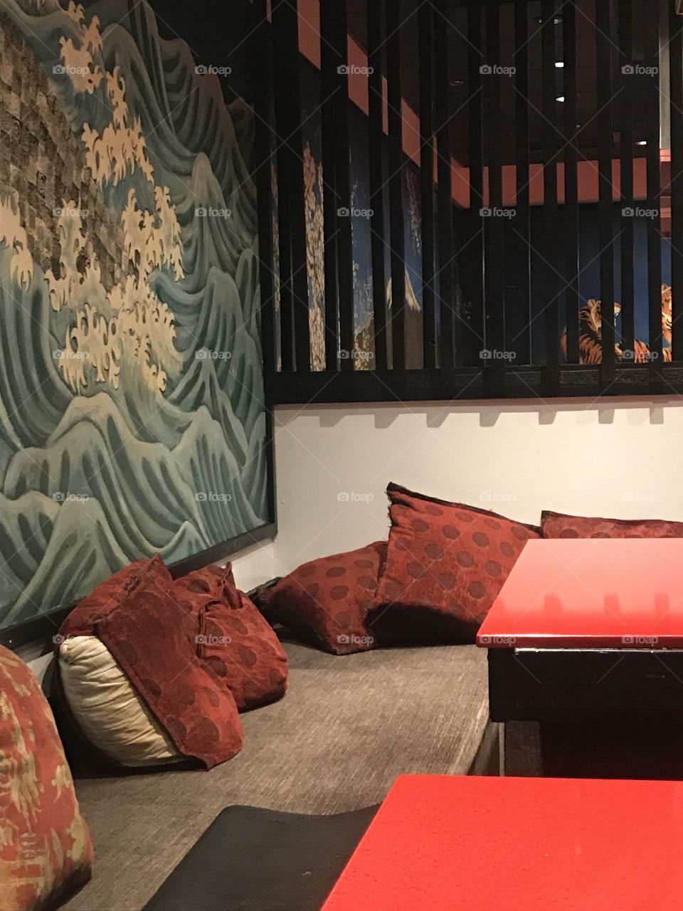 Red decorative pillows laying between a blue picture wall and a red counter. 