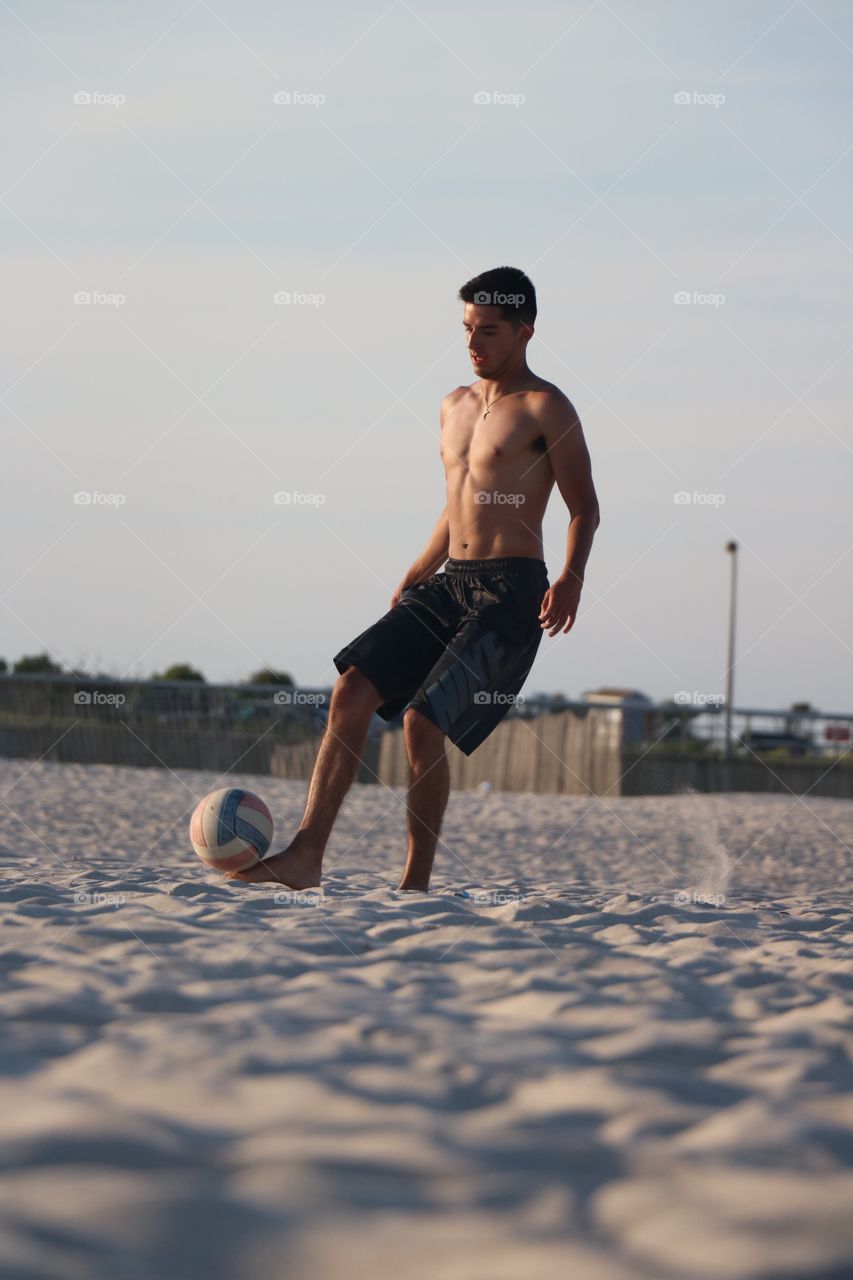 Man playing football on beach