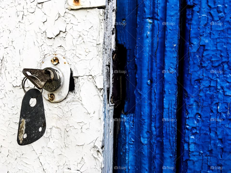 Wooden old door with key. Blue and white wooden background. 