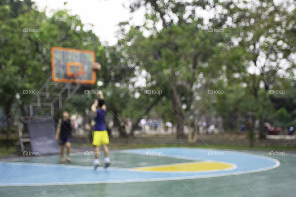 Blurry image teens playing basketball in the morning at BangYai Park , Nonthaburi in Thailand.