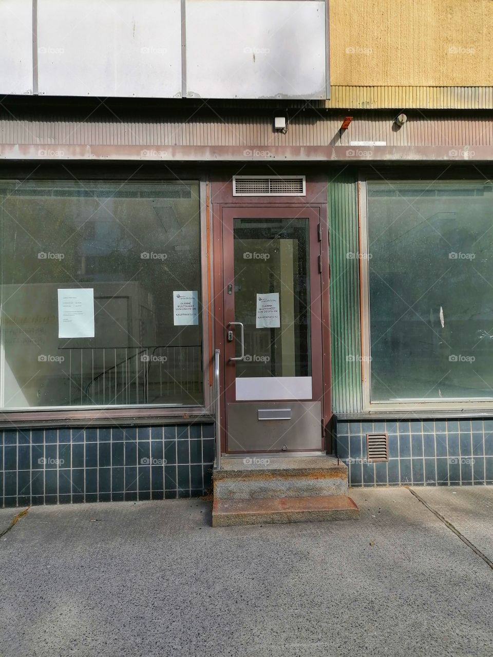An old dilapidated building in the middle of a town that used to be a shop. No one walks through this door anymore. Sad.